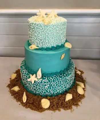 Wedding cake with blue frosting, sand and shells