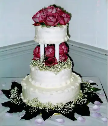 Wedding cake topped with fresh red roses and baby's breath