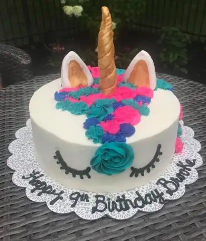 Unicorn birthday cake with gold horn and pink and blue frosting