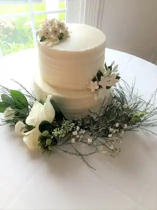 Wedding cake with fresh flowers beside a dessert display